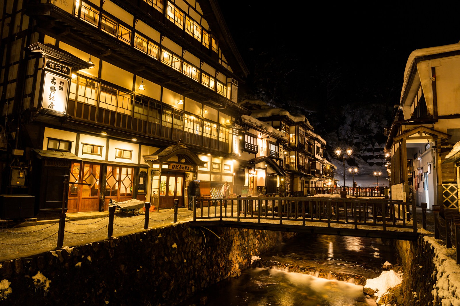 夜間にライトアップされた銀山温泉街の町並み。積雪と木造建築のロマンチックな景観
