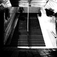 地下通路の階段をしょんぼり上る人（モノクロ）の写真