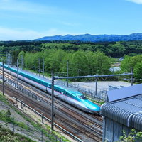 北海道新幹線と山々が見える線路沿いの風景の写真
