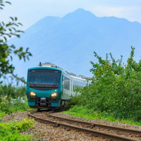 林檎畑を走るローカル線の青い列車と岩木山の風景の写真