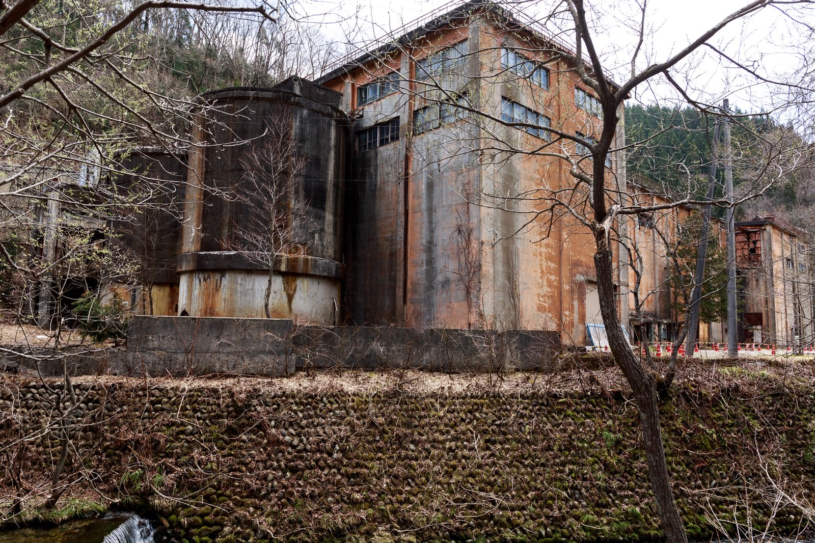 古遠部鉱山跡のさびた鉄製タンクと廃墟建物