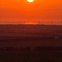 水面に映る夕日が沈む風車のある田園風景の写真