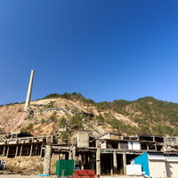 尾去沢鉱山跡の廃墟と青空、露出した山肌とコンクリート建造物の写真
