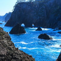 山の稜線から昇るオレンジの満月と水面の写真