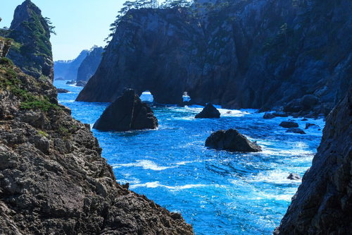 山の稜線から昇るオレンジの満月と水面