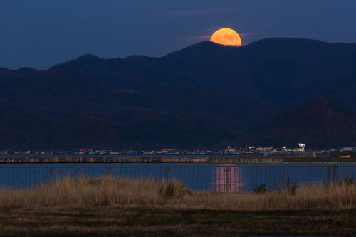 山並みに昇るスーパームーン 水面に映る月光