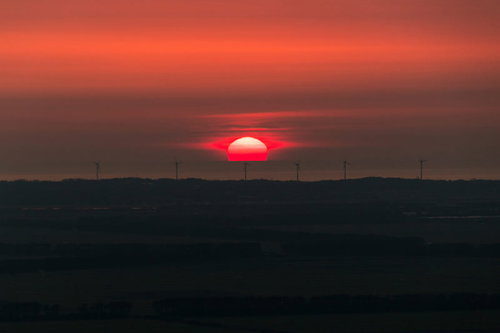 風力発電所の地平線に沈む夕日と風車のシルエット
