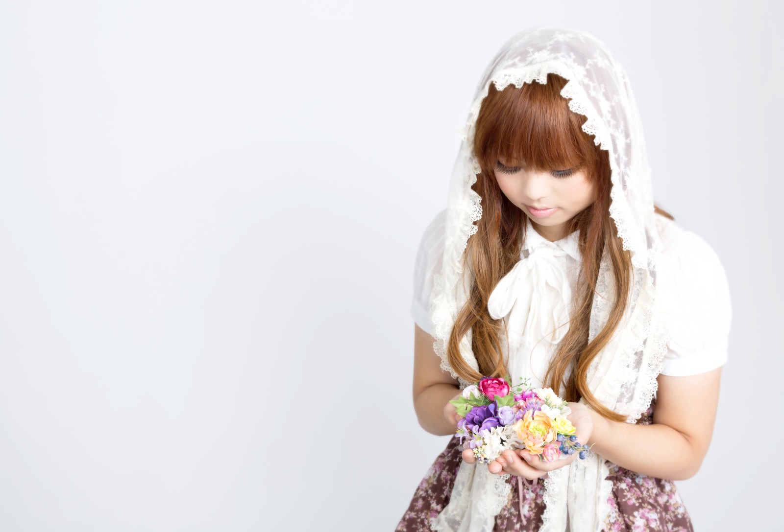 白いレース付きヘッドドレスをかぶり、カラフルな造花を両手に持つ女の子の写真［モデル：あみ］