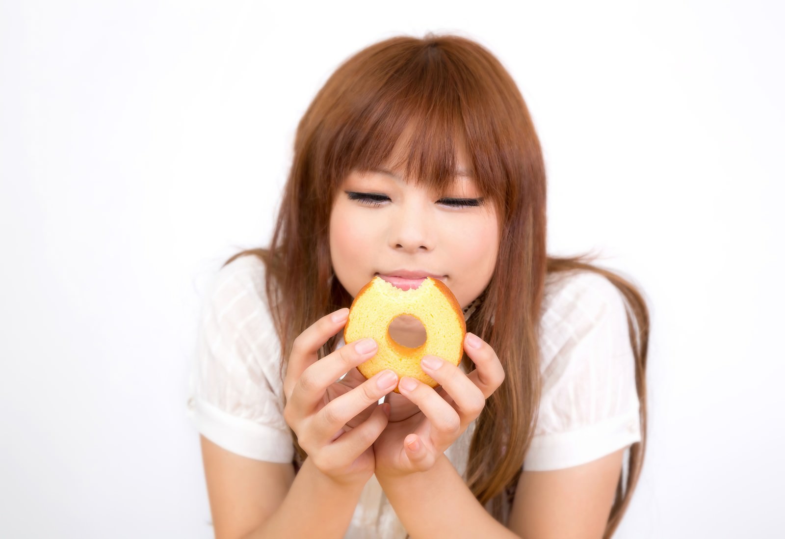 バームクーヘンを食べながら目を閉じている女の子［モデル：あみ］