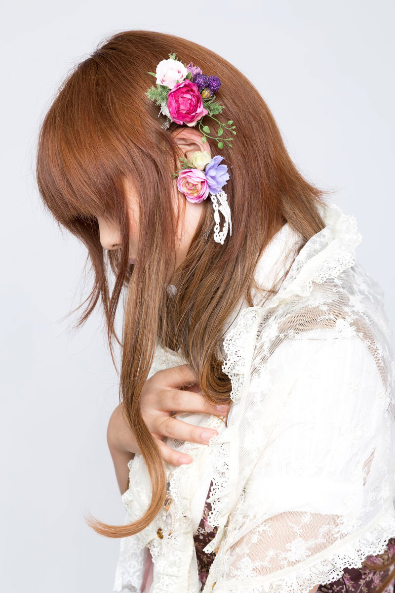 花のイヤリングをした茶髪ロングの女性が白いレーストップスで横向き［モデル：あみ］