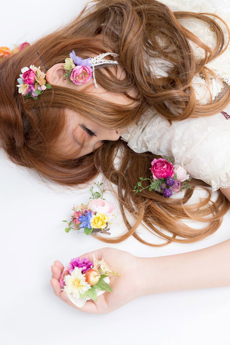 ピンク色の造花冠をつけた女の子がレース素材の衣装で眠っている［モデル：あみ］