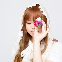 指先に造花を持って目を閉じる女性の写真