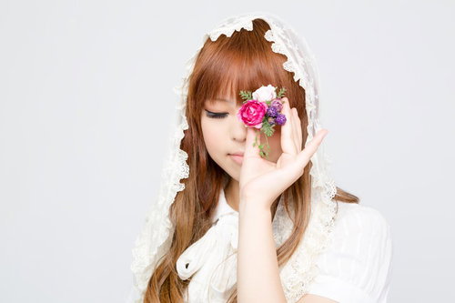 指先に造花を持って目を閉じる女性