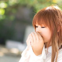 両手を口元に当てて息を温める女性の写真