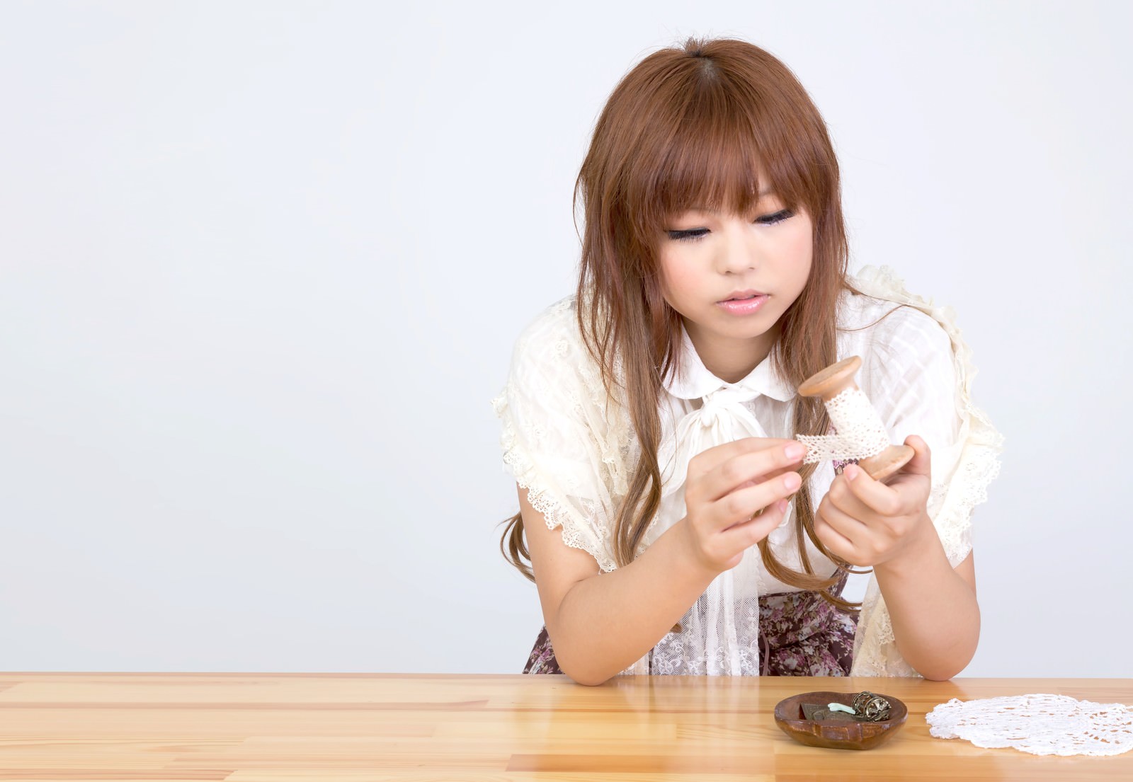 木製テーブルでレース素材を使った手芸をする女の子［モデル：あみ］