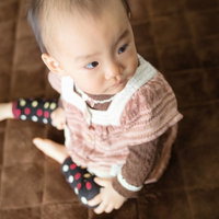 おもちゃを握って上を見上げる赤ちゃんの写真
