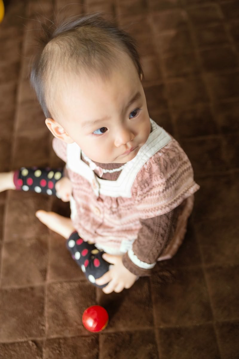 おもちゃを持ち上を見上げる赤ちゃん［モデル：あんじゅ］
