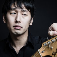 黒いシャツを着たギタリストがストラトキャスターをチューニングの写真