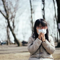 花粉の飛散を気にしてマスクを押さえる女の子の写真
