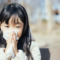 花粉症がつらみ、ティッシュで鼻をかむ少女の写真