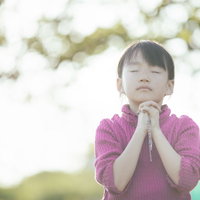 両手を合わせて祈るクリスチャンの女の子の写真