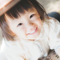 室内で上から見下ろして撮った白い服の笑顔の幼児の写真
