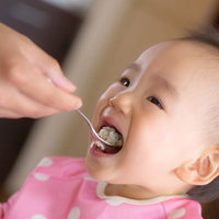 スプーンでごはんを食べる赤ちゃんの写真