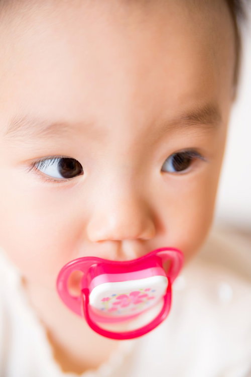 赤いおしゃぶりをくわえた赤ちゃんの顔