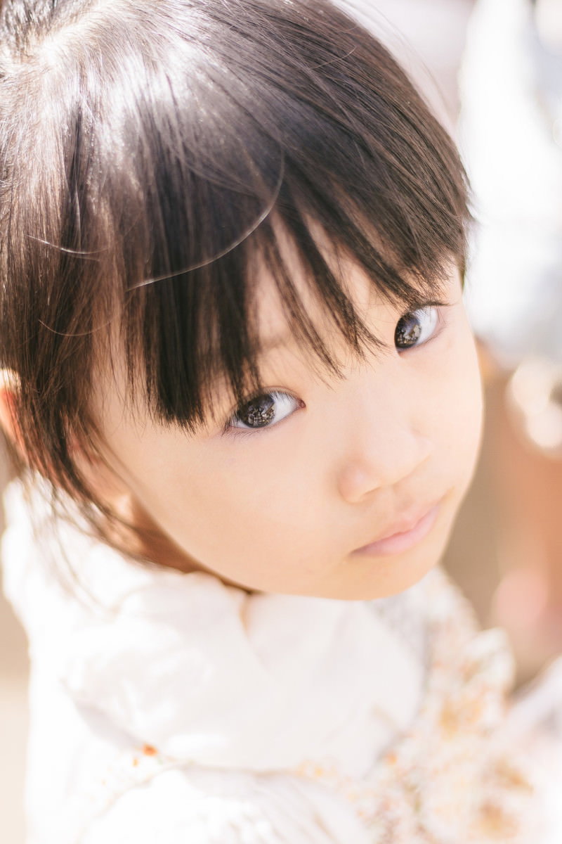 白い服の子どもが上目遣いで見つめるポートレート［モデル：あんじゅ］