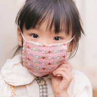 ピンクのマスクとエプロンをした女の子が笑顔の写真