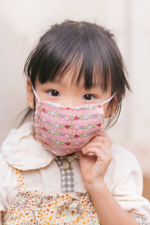 ピンクのマスクとエプロンをした女の子が笑顔