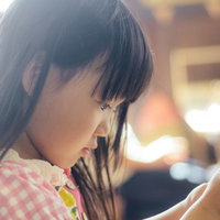 チェック柄の服を着て工作に夢中の女の子の写真