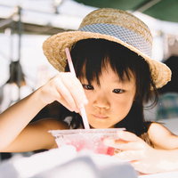 かき氷を食べる麦わら帽子姿の女の子、屋外で夏休みを楽しむの写真