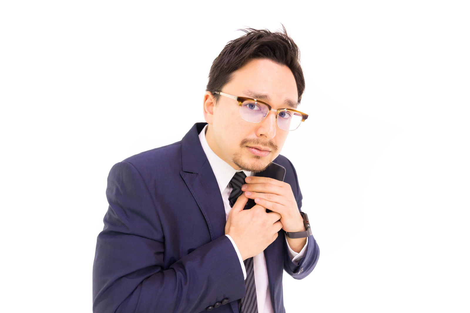 心配そうな表情でスマートフォンを覗き込む紺色スーツの男性［モデル：Max_Ezaki］