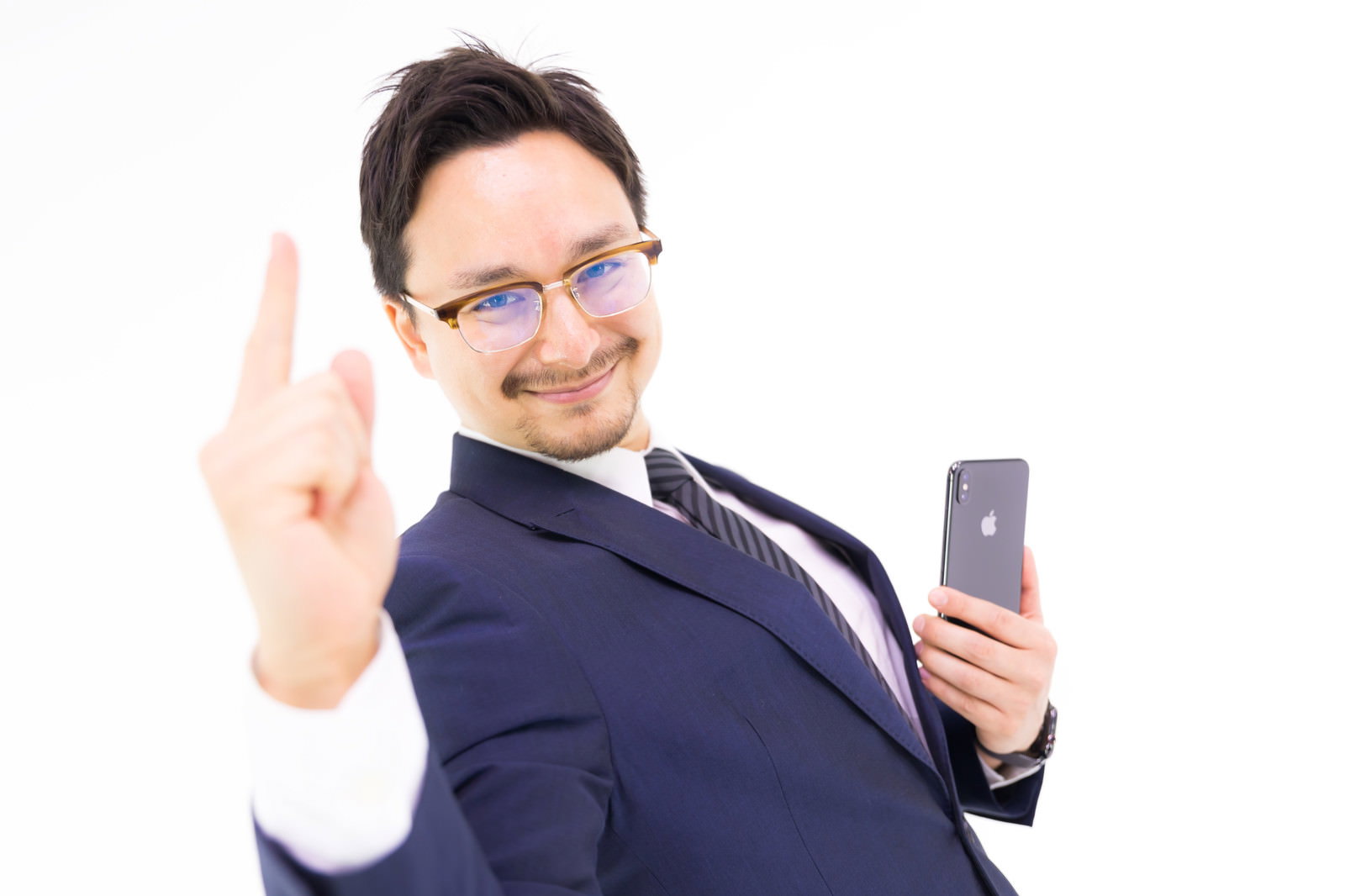 紺色のスーツを着た眼鏡の男性がスマートフォンを持ちピースサインをしている［モデル：Max_Ezaki］