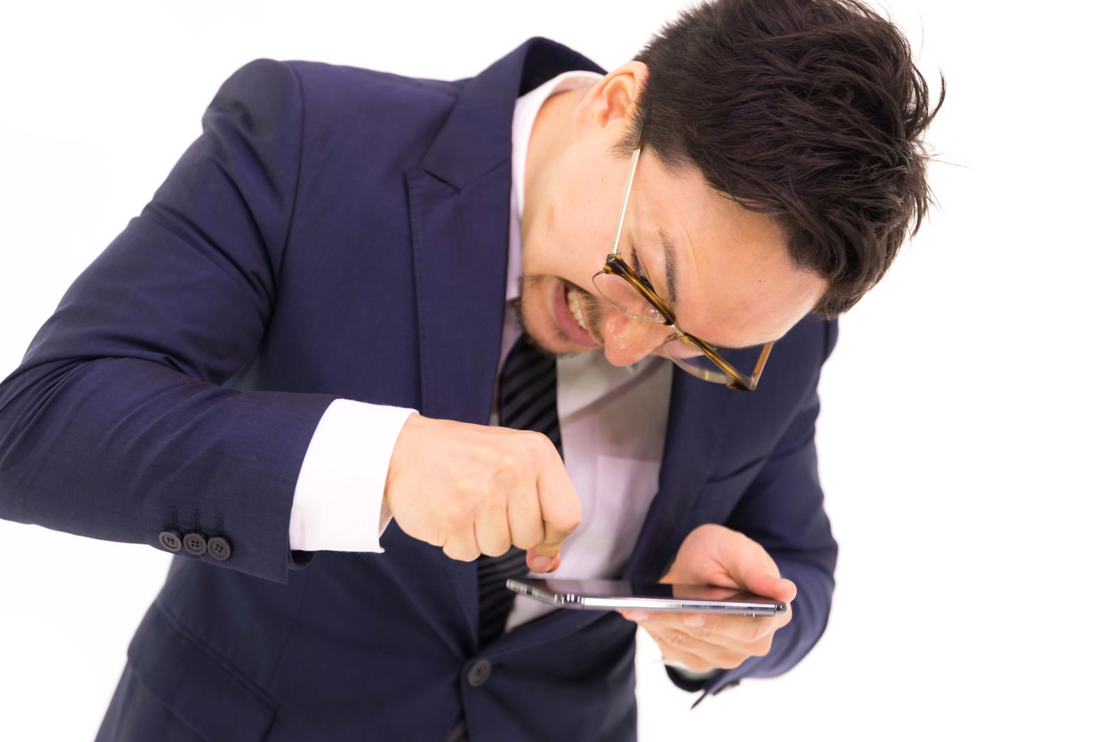 スマートフォンを叩こうとする怒ったスーツ姿の男性［モデル：Max_Ezaki］
