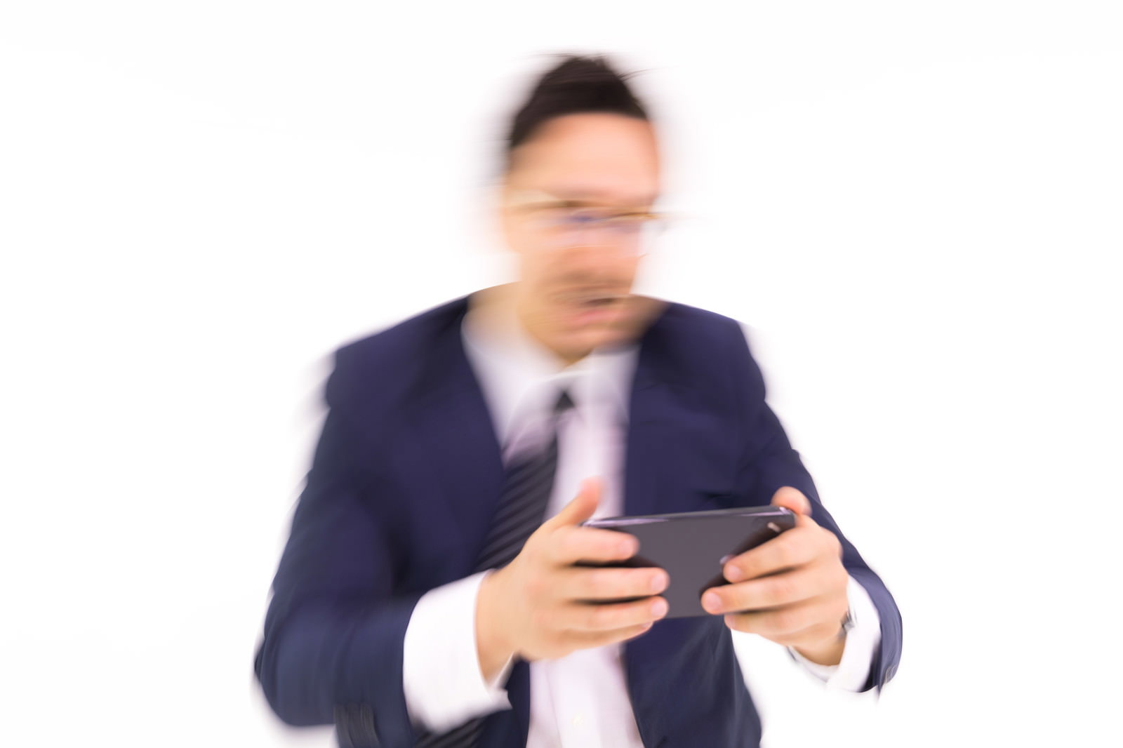 スマートフォンを見て驚いている紺色スーツの男性［モデル：Max_Ezaki］