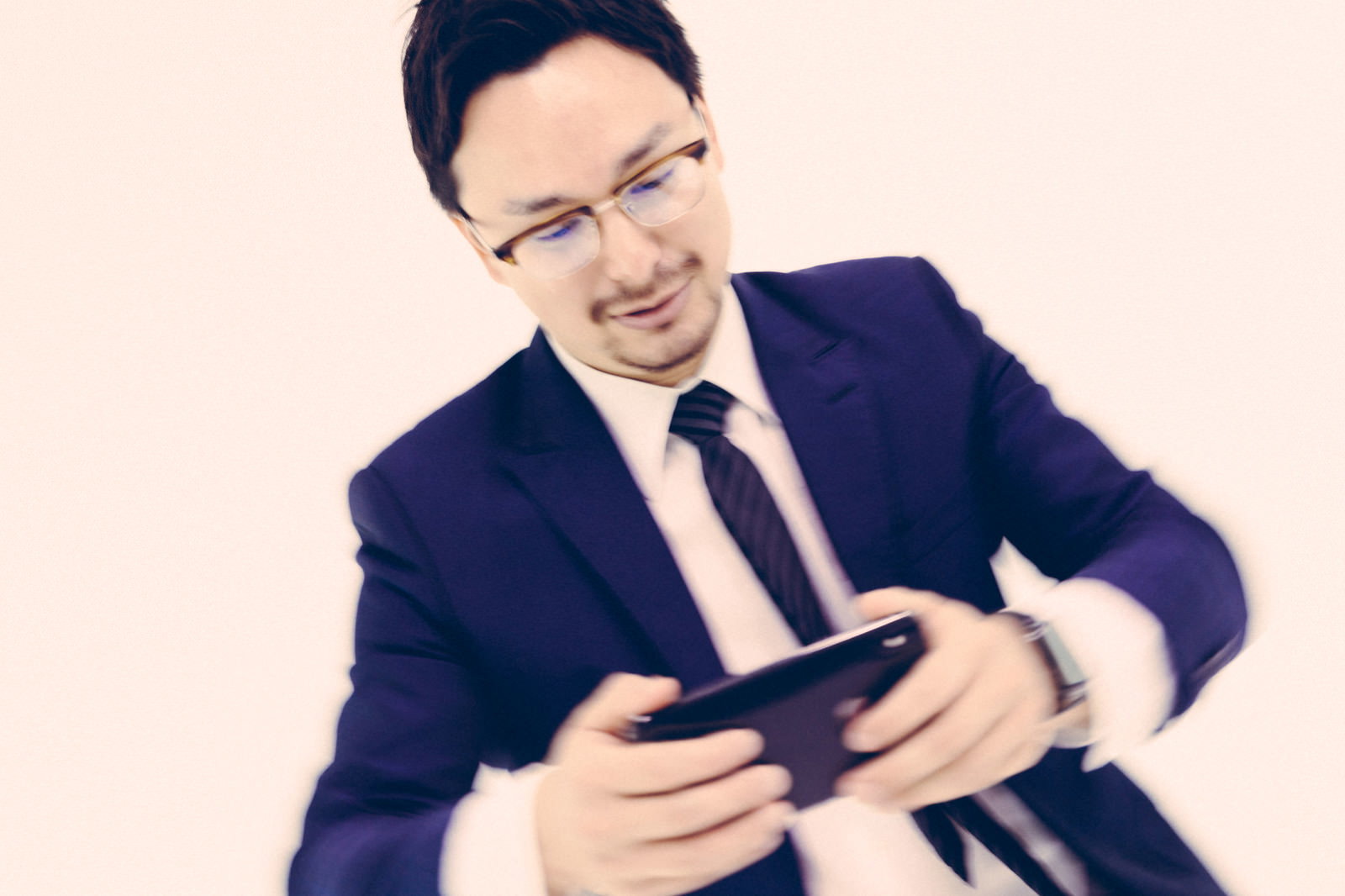 スマートフォンが動かず困惑するスーツの男性［モデル：Max_Ezaki］