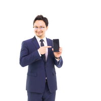 スマホを指差すスーツ姿のビジネスマンの写真