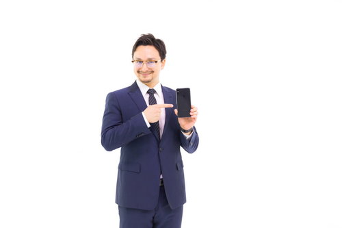 スマホを指差すスーツ姿のビジネスマン
