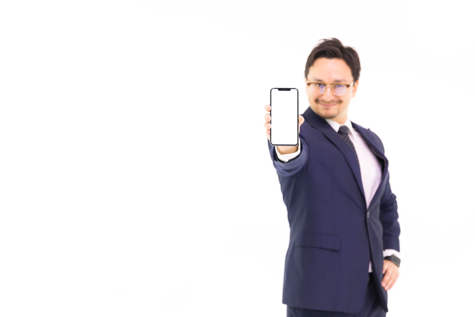 iPhoneの画面をカメラに向けて差し出すスーツ姿の男性［モデル：Max_Ezaki］