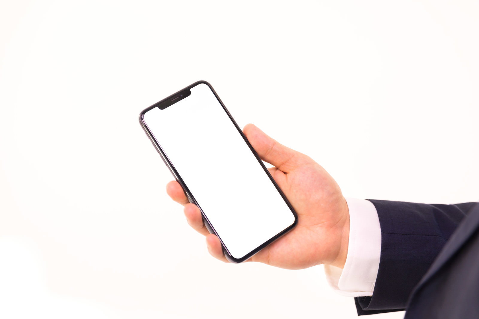 スーツの男性の手がiPhone XS Maxを持っている［モデル：Max_Ezaki］