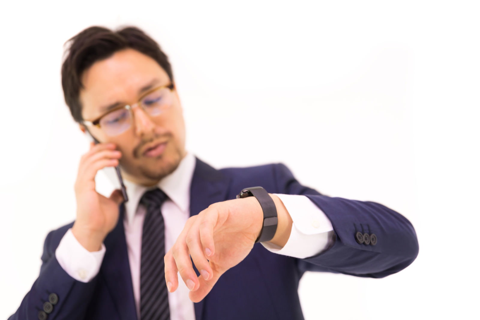 電話しながらスマートウォッチを確認するスーツ姿の男性［モデル：Max_Ezaki］