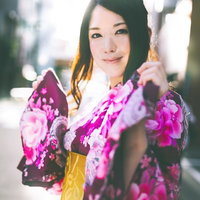 黄色い帯の花柄浴衣を着て立つ黒髪の女性の写真