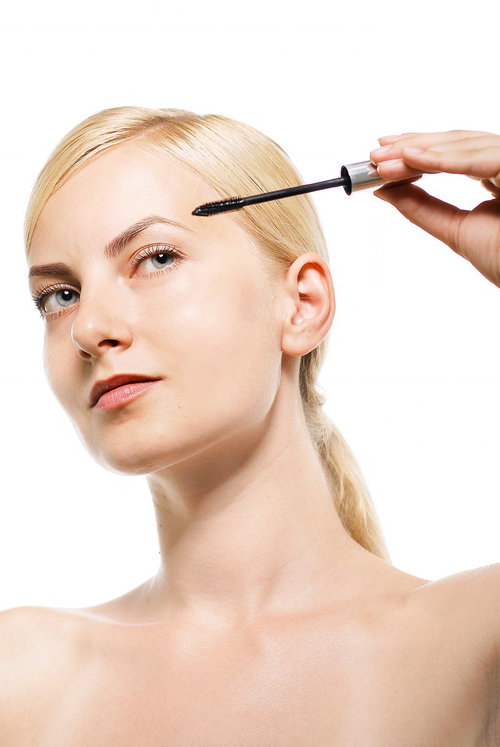 マスカラを眼に構える金髪の女性のビューティ