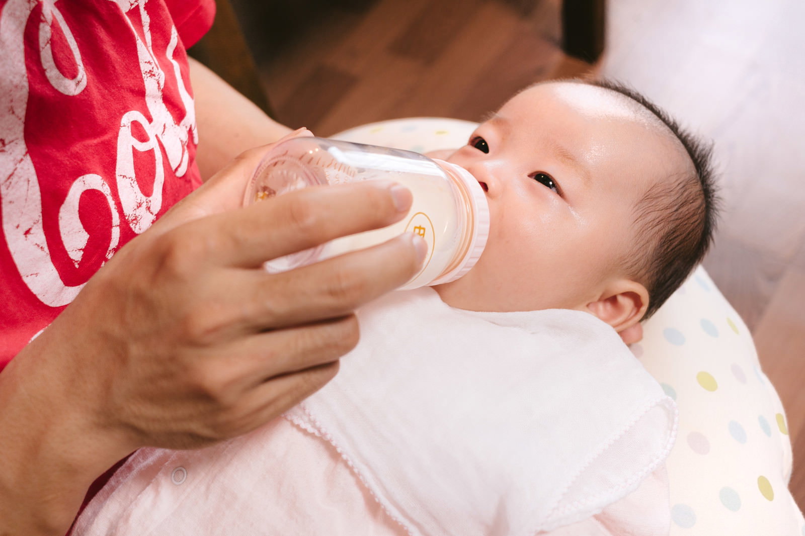 母親に抱かれて哺乳瓶を飲む赤ちゃん