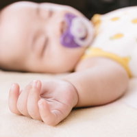 赤ちゃんのむっちりな手とおしゃぶりでお昼寝の写真