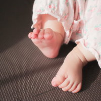 むっちむちのピンクベビーウェア姿の赤ちゃんの両足の写真