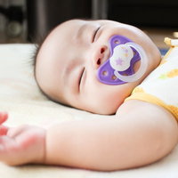 おしゃぶりを咥えてスヤスヤ眠る赤ちゃんの寝顔の写真
