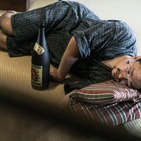 お酒を飲みすぎて畳の上で寝落ちする外国人男性の写真